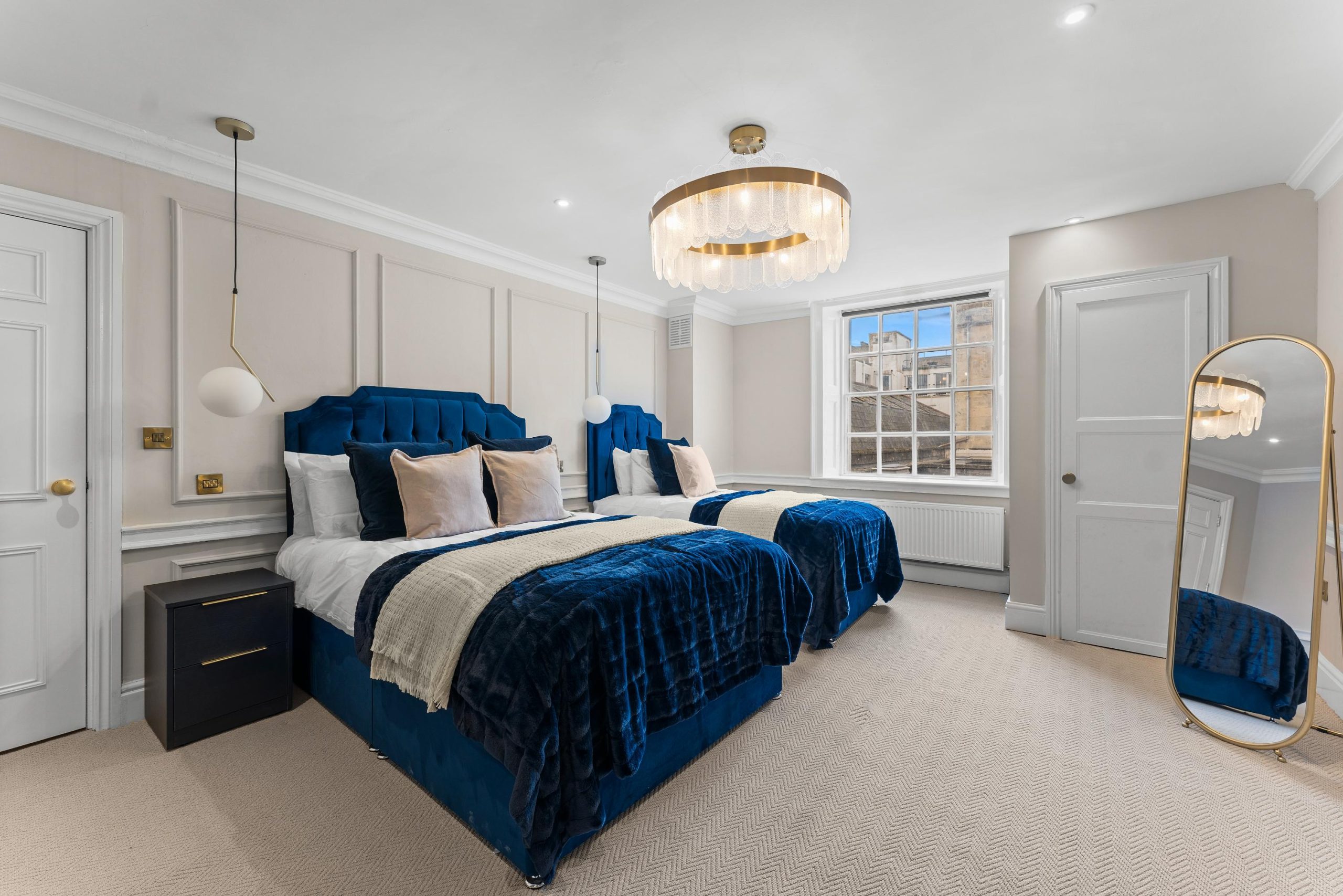 Twin bedroom with deep-blue upholstered beds and neutral décor