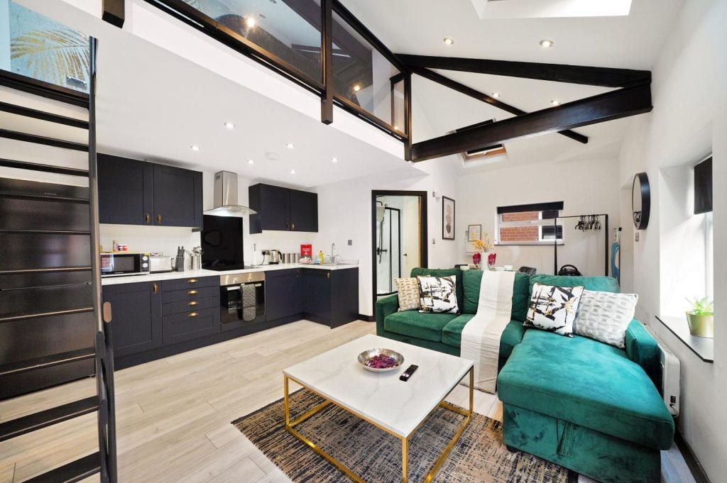 Duplex apartment with exposed beams, a green sofa and an open-plan kitchen